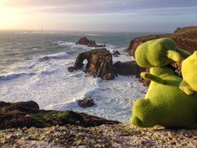 kleiner Drache Roloc schaut von den Steilklippen in Cornwall aufs offene Meer